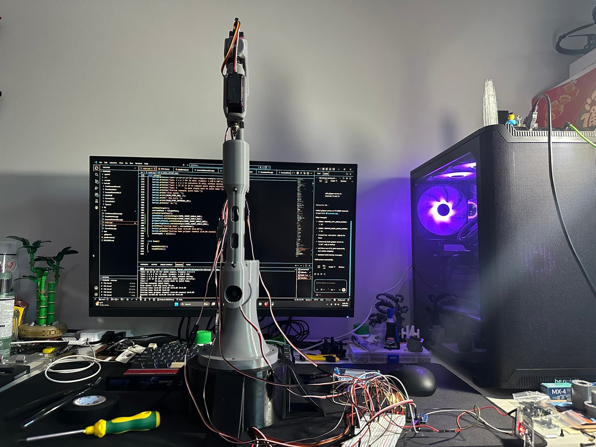 Full six-axis robotic arm assembled on a desk beside its control electronics