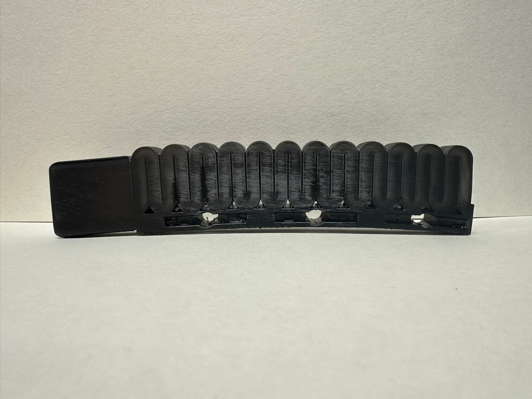 Black additively manufactured variable-stiffness soft robotic finger shown straight against a neutral background