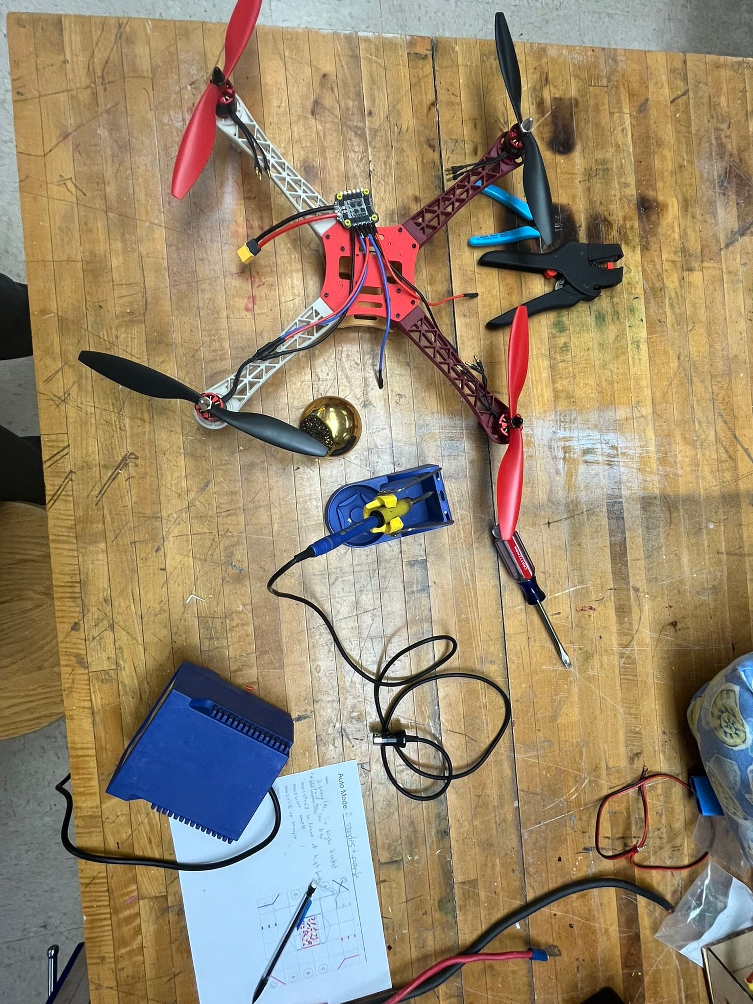 Partially assembled Nylon-CF quadcopter with motors, propellers, wiring, and flight electronics during workshop integration